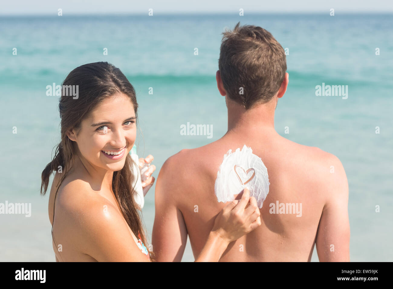 Woman putting sun tan lotion on her boyfriend Stock Photo