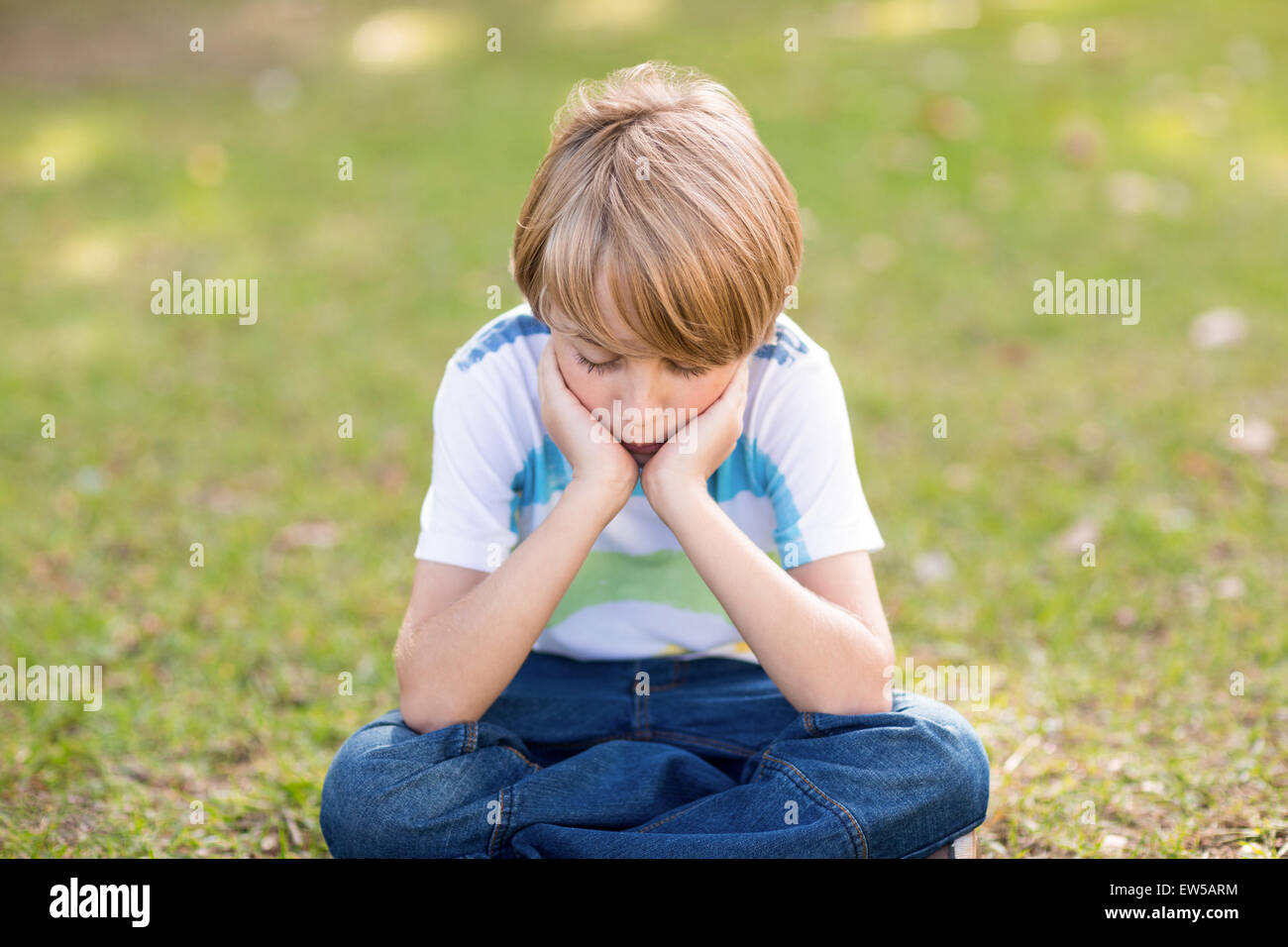 Little boy feeling sad in the park Stock Photo