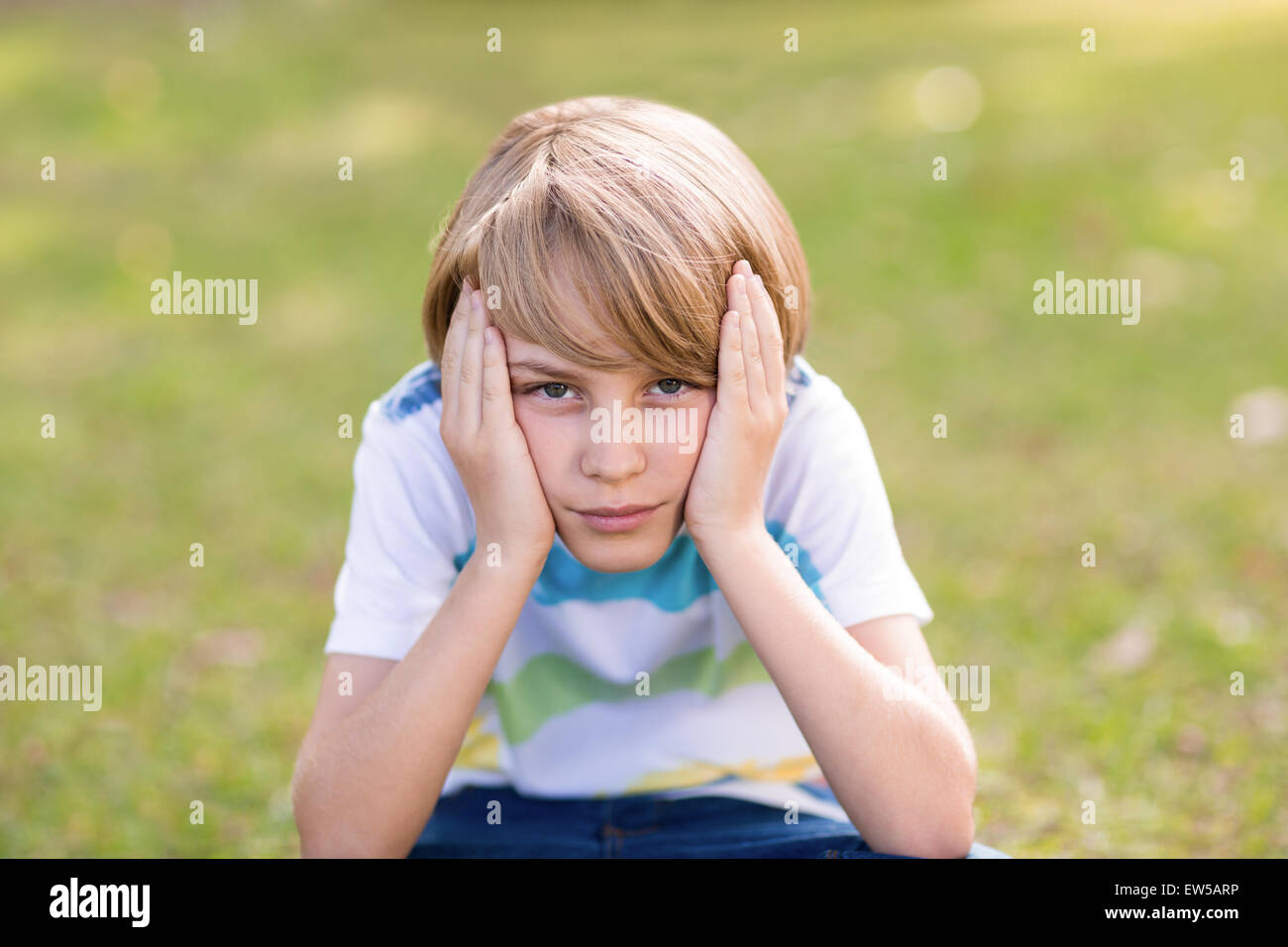 Little boy feeling sad in the park Stock Photo