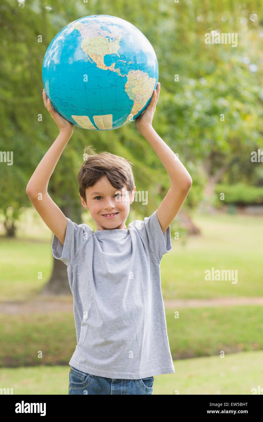 Smiling boy holding an earth globe in the park Stock Photo