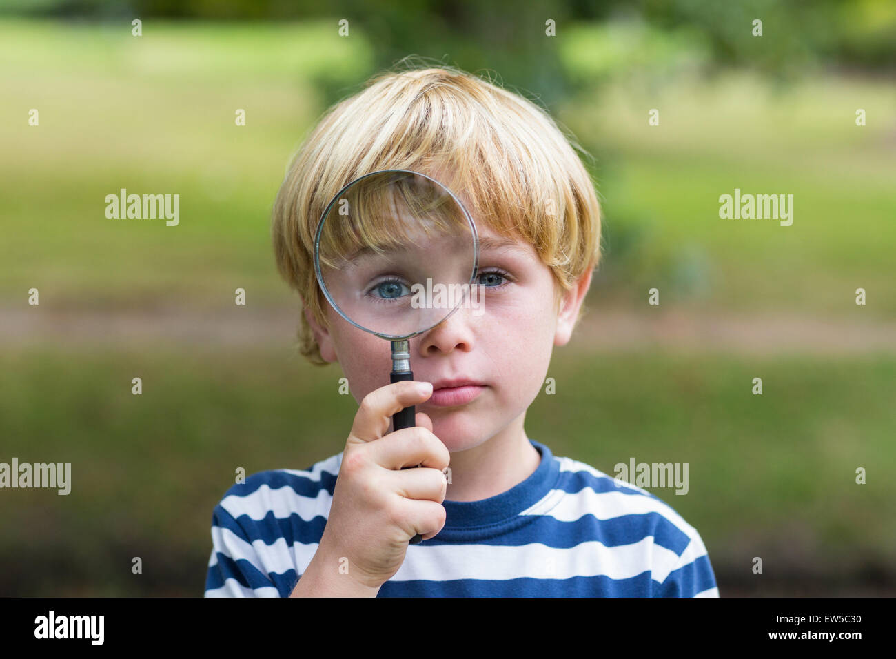 Curious little boy looking through magnifying glass Stock Photo