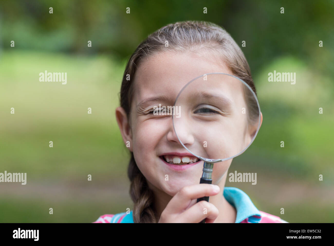 Curious little girl looking through magnifying glass Stock Photo