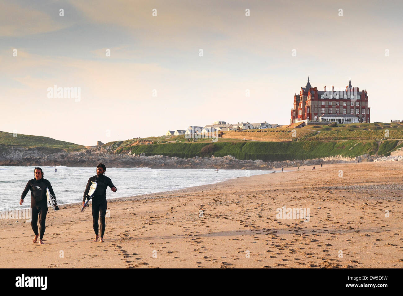 Two surfers walking along Fistral Beach in Newquay in Cornwall. UK. Stock Photo