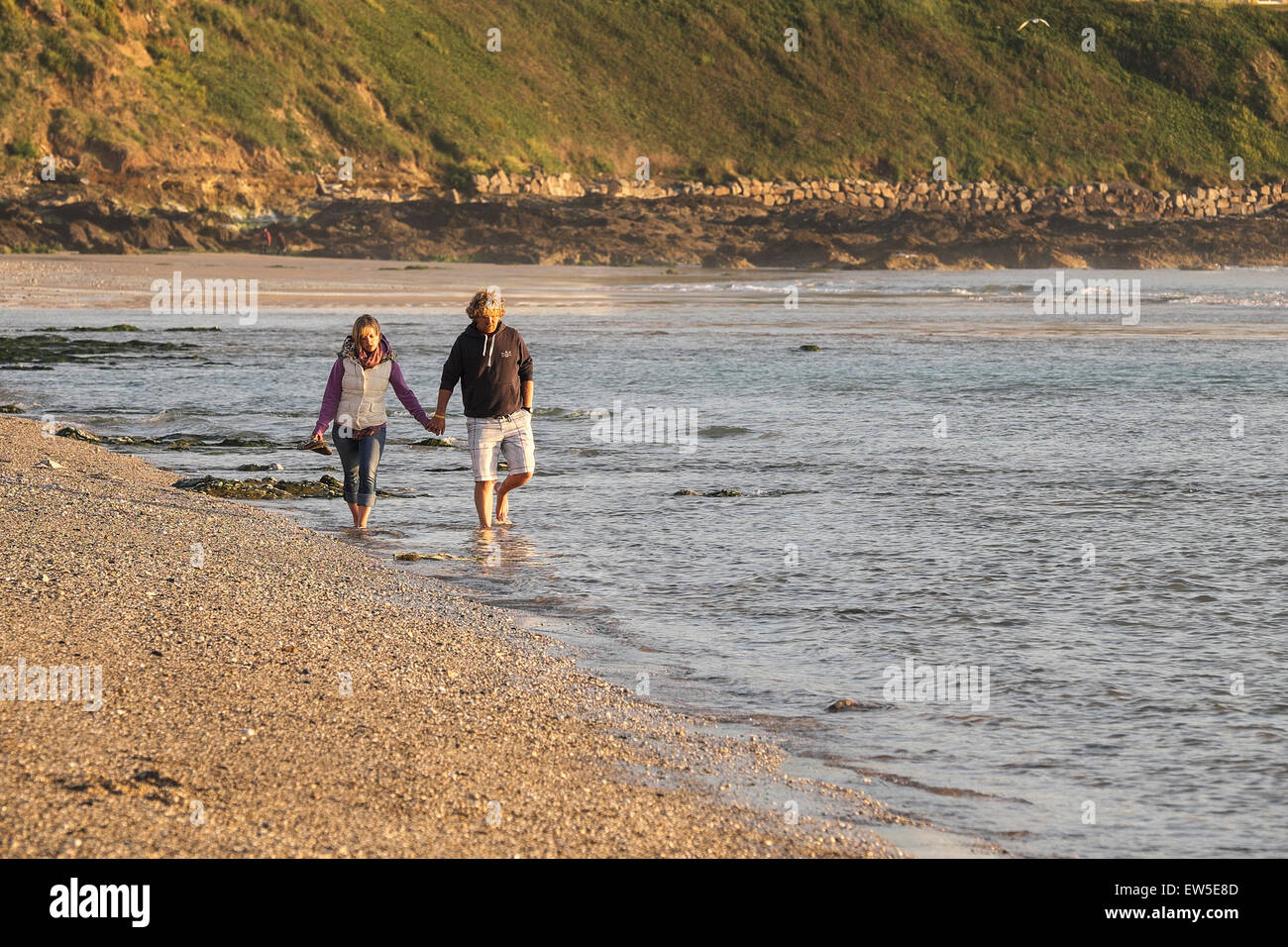 A couple strolling along the shoreline on Fistral beach. Stock Photo