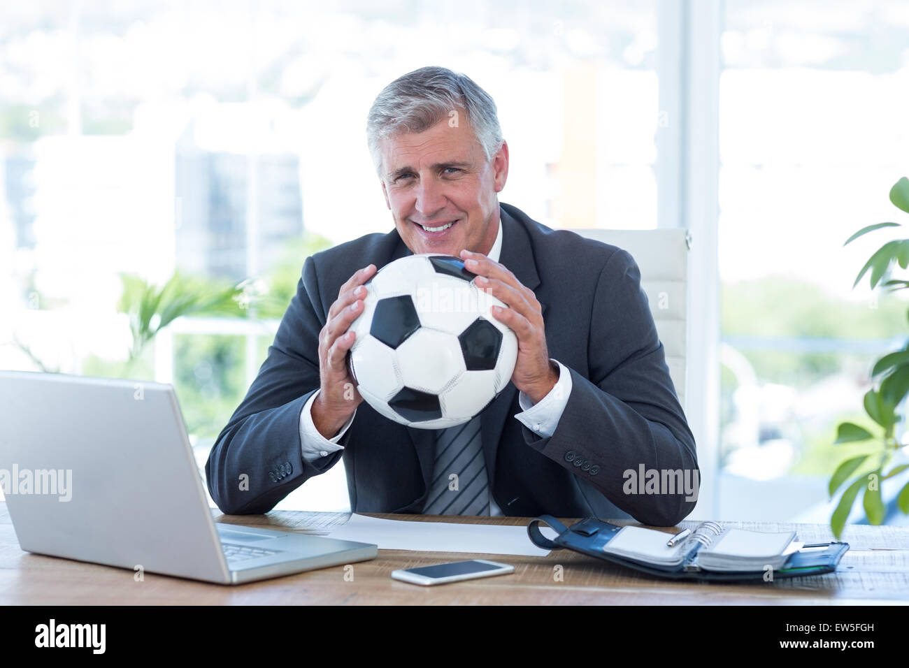 Smiling businessman holding soccer ball Stock Photo - Alamy