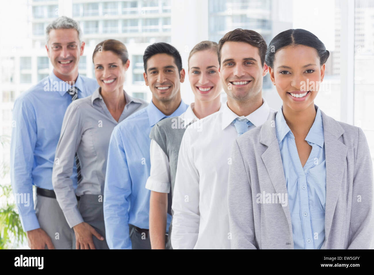 Happy business people looking at camera in a row Stock Photo - Alamy