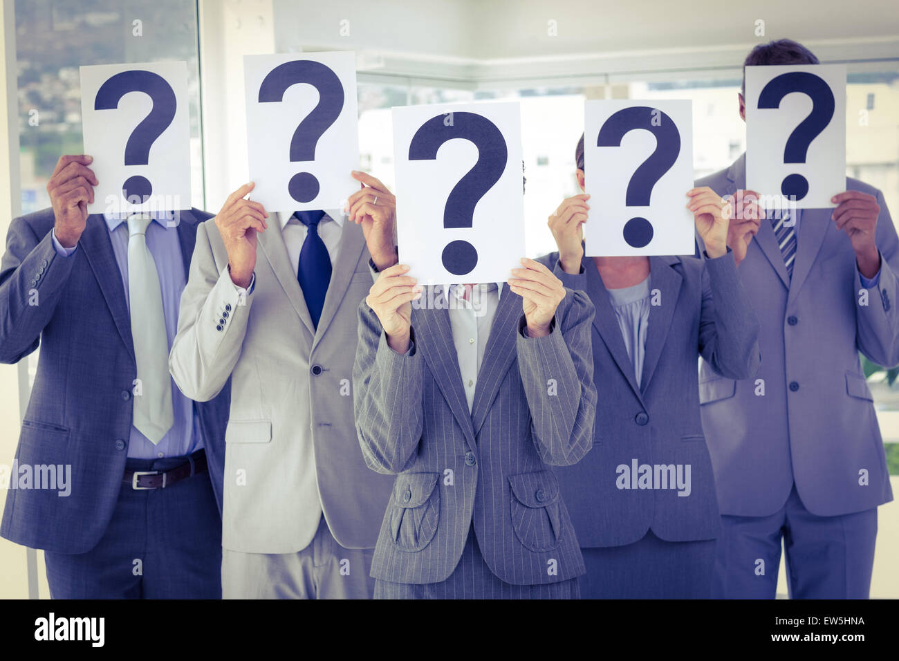 Business team holding question marks over face Stock Photo