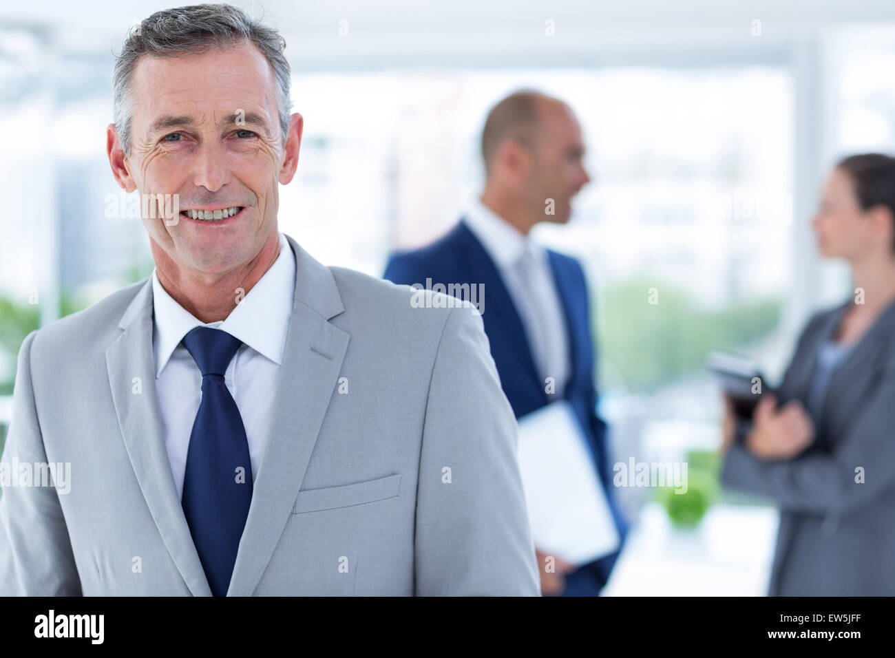businessman smiling with two colleague behind him Stock Photo - Alamy