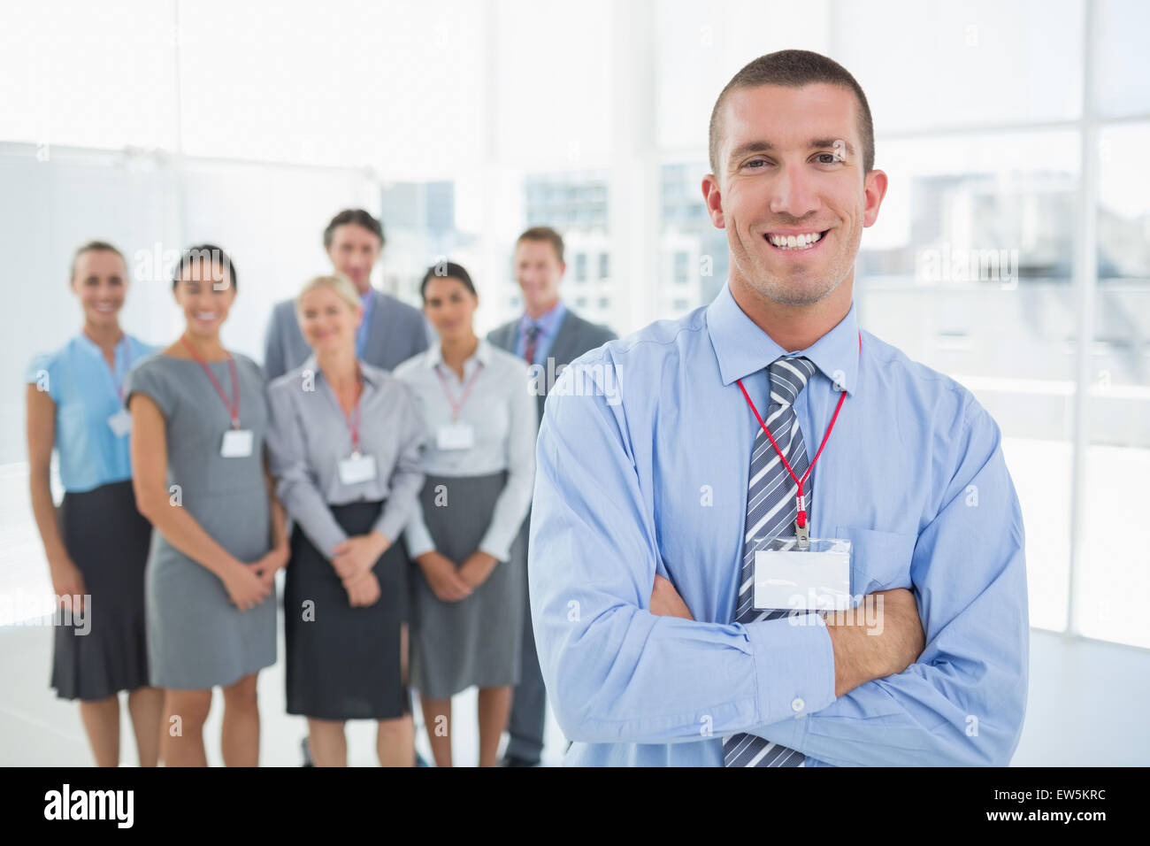 Businessman smiling at camera with team behind him Stock Photo - Alamy