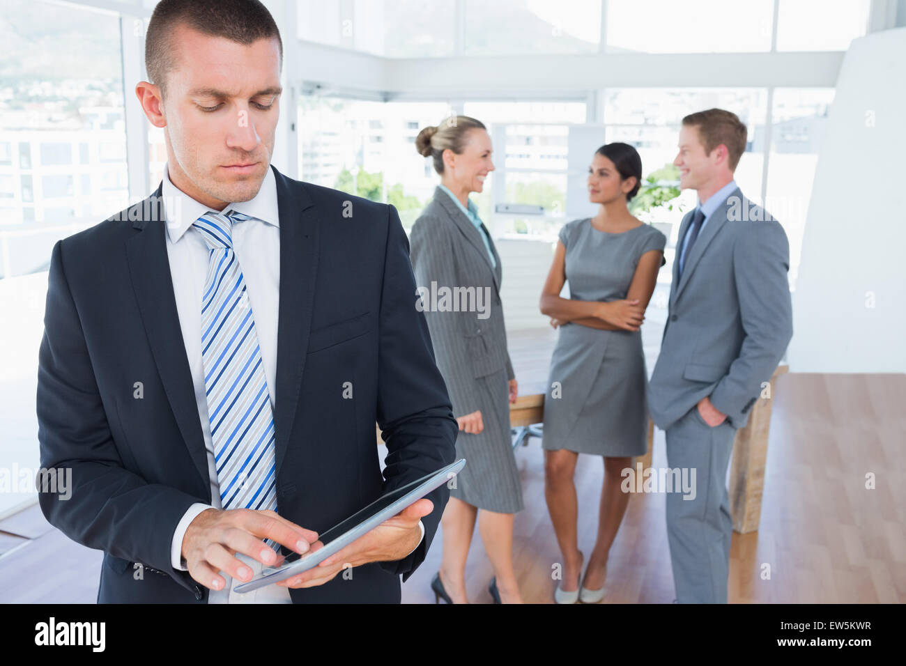 Businessman using tablet with colleagues behind him Stock Photo - Alamy