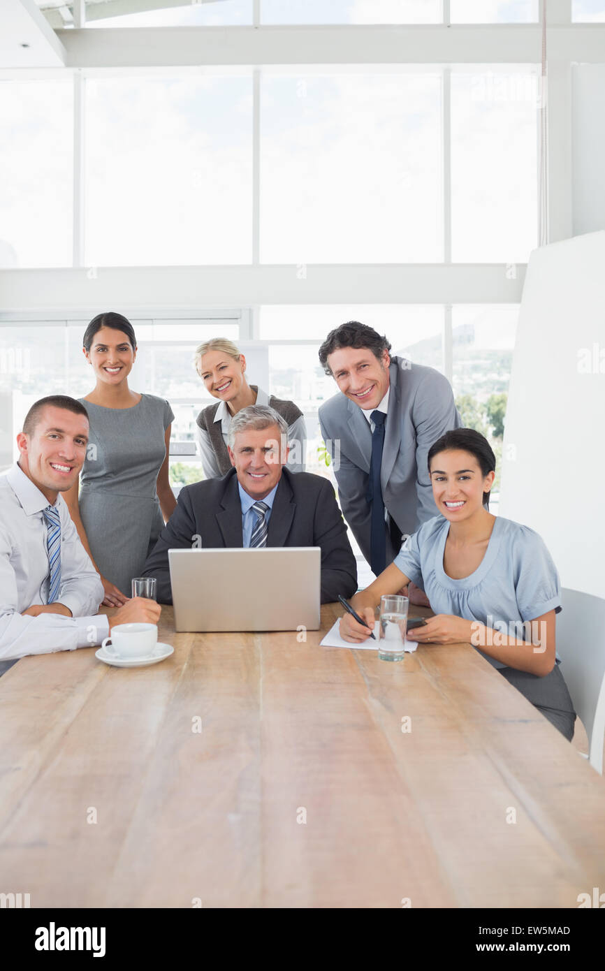Smiling business team working together on laptop Stock Photo - Alamy