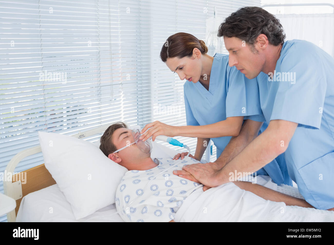 Worried doctors doing heart massage and holding oxygen mask Stock Photo