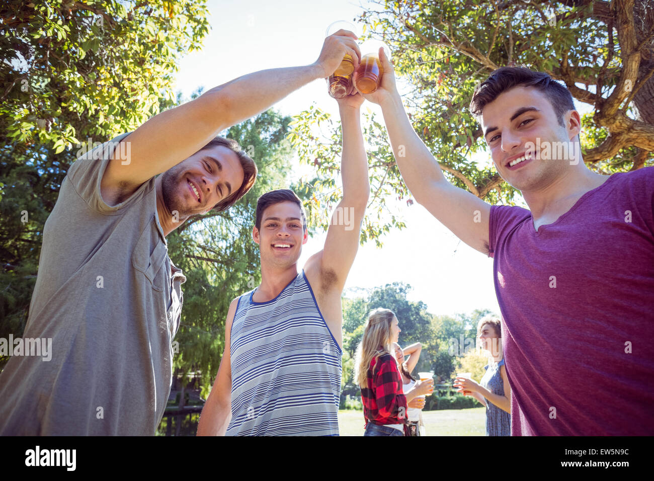 Happy friends in the park having beers Stock Photo - Alamy
