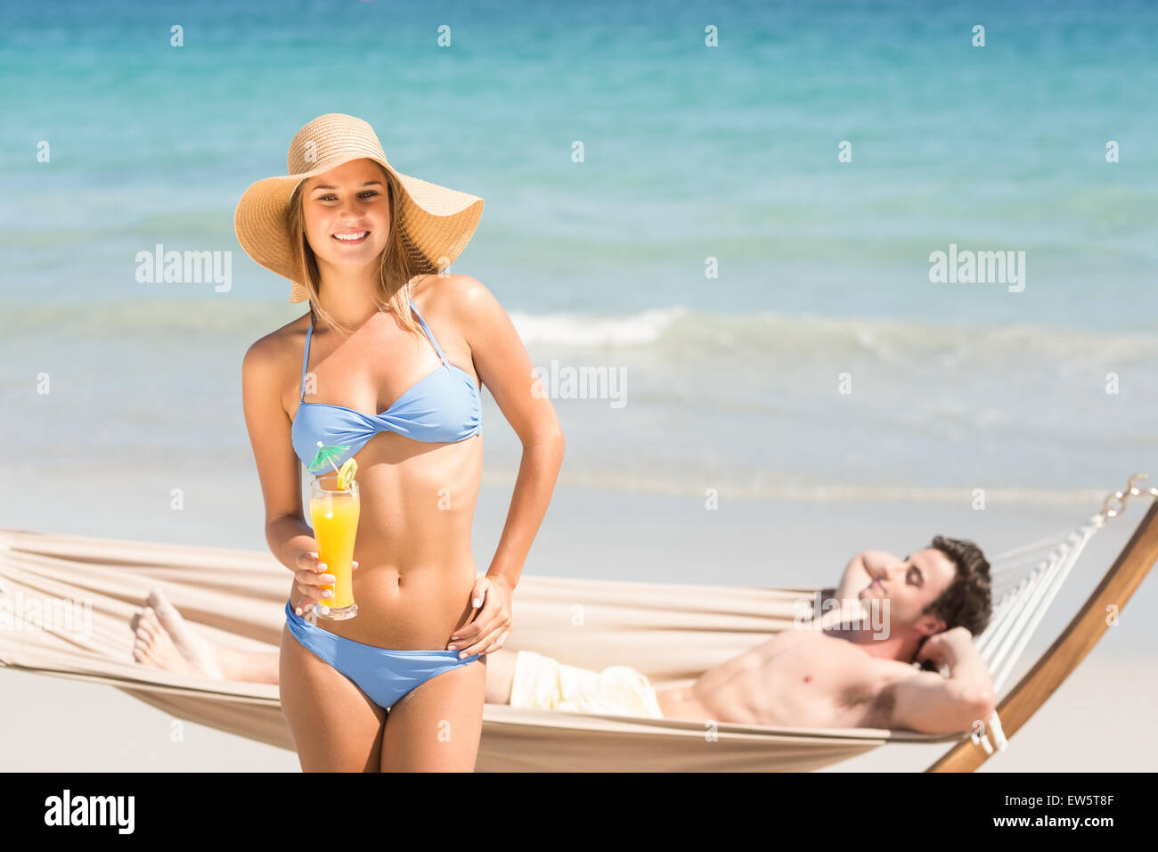 Pretty woman looking at camera while her boyfriend relaxing on the hammock Stock Photo