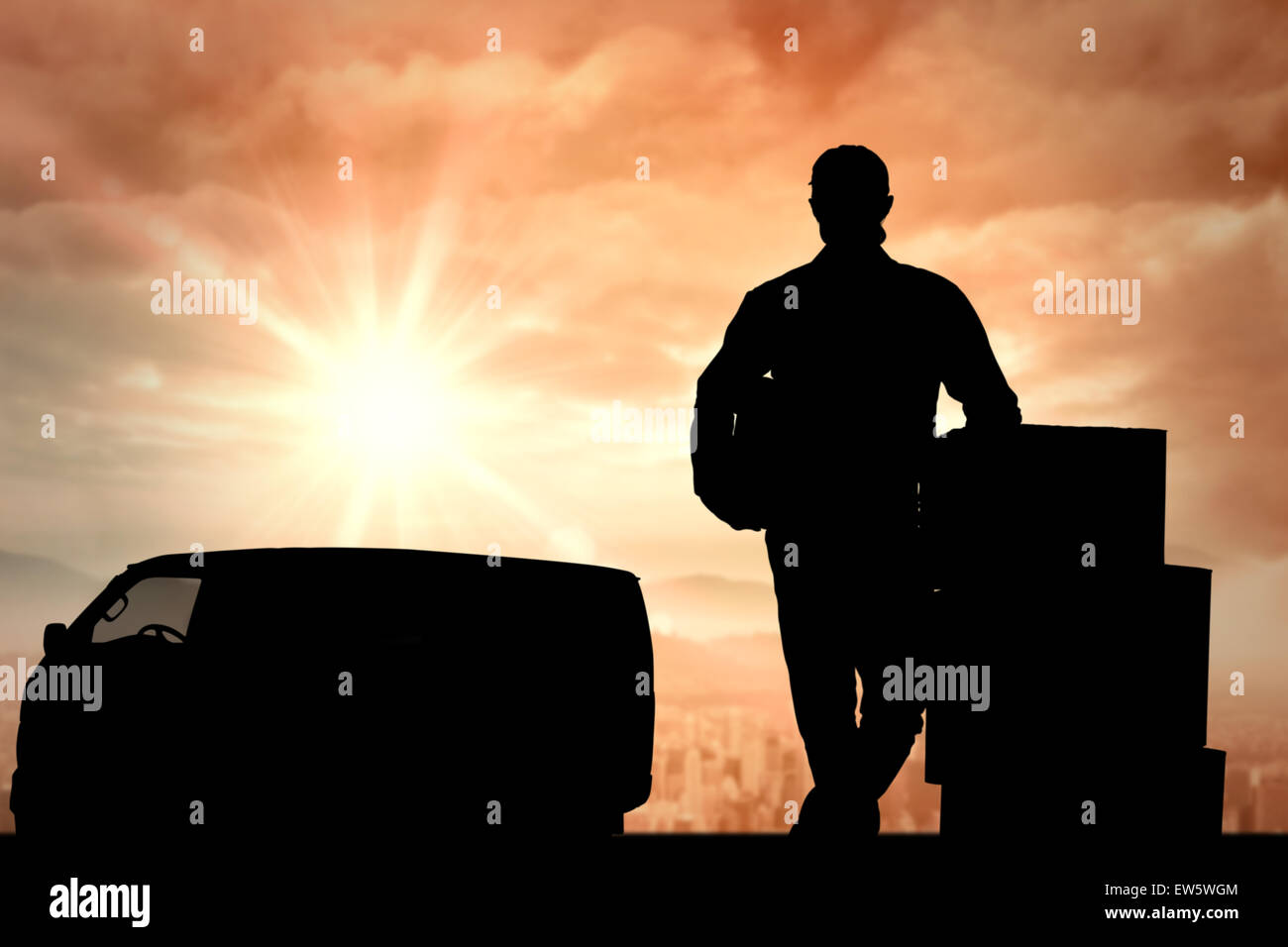 Composite image of handsome delivery man leaning on stacked cardboard boxes Stock Photo