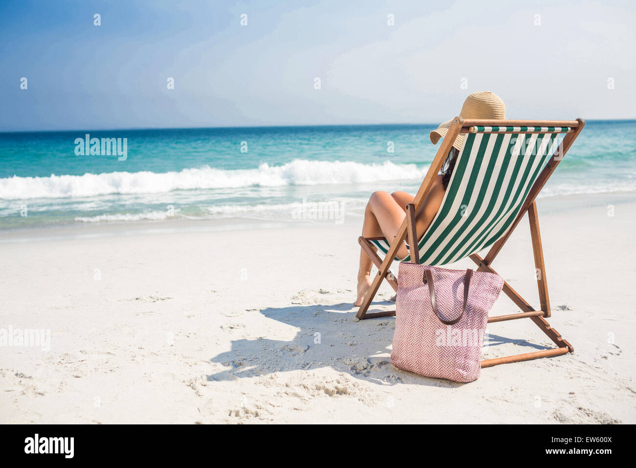 Rear view of pretty brunette relaxing on deck chair at the beach Stock ...