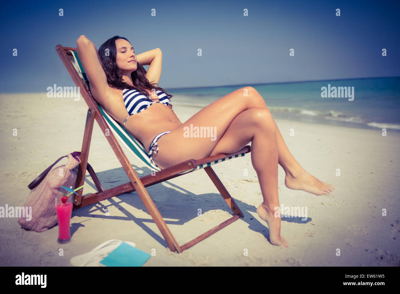 pretty-brunette-relaxing-on-deck-chair-at-the-beach-stock-photo-alamy
