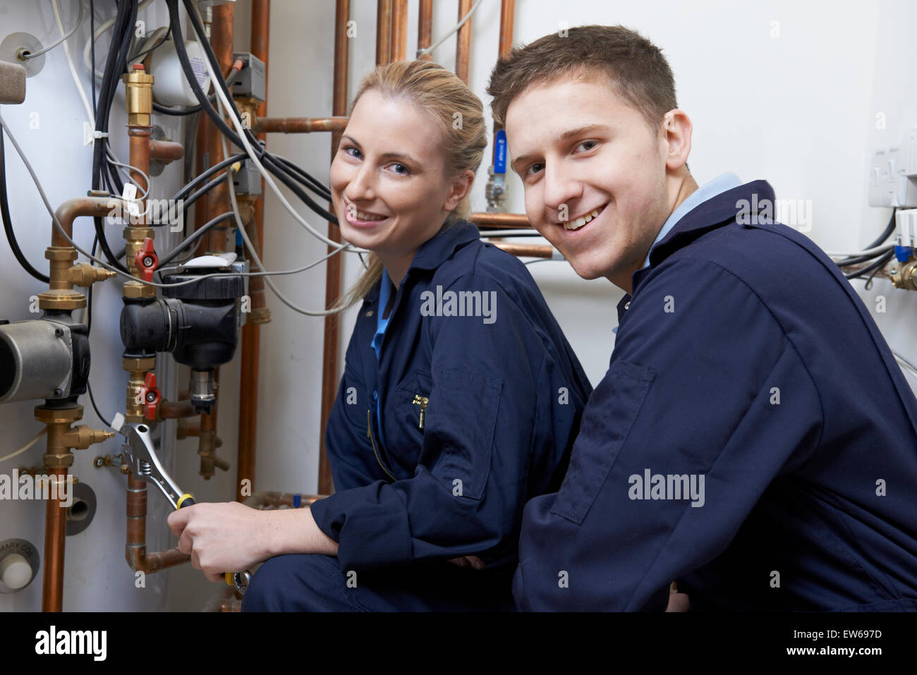 Female Trainee Plumber Working On Central Heating Boiler Stock Photo