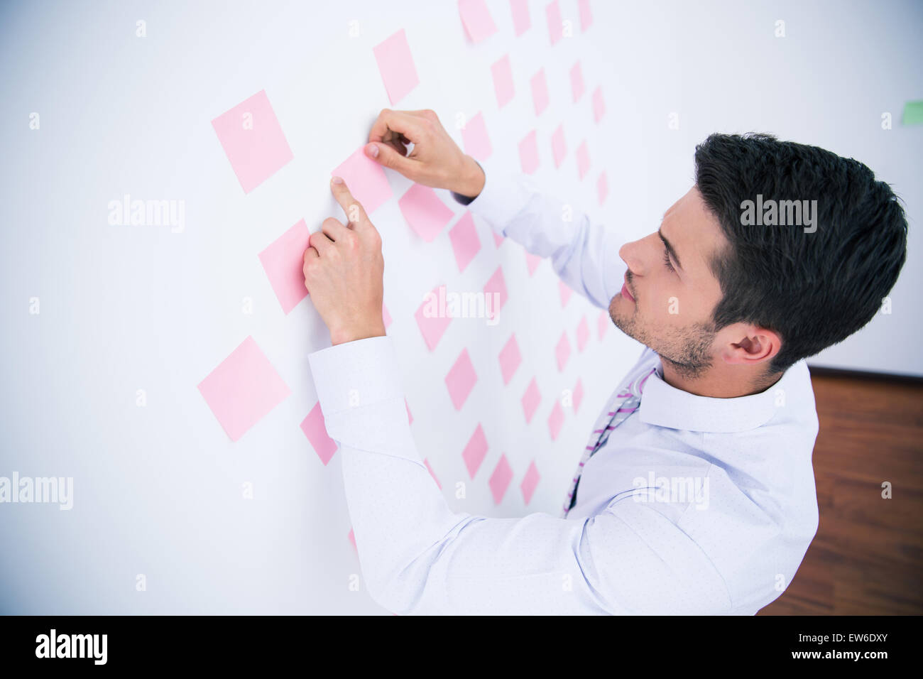 Businessman looking at sticker on wall in office Stock Photo
