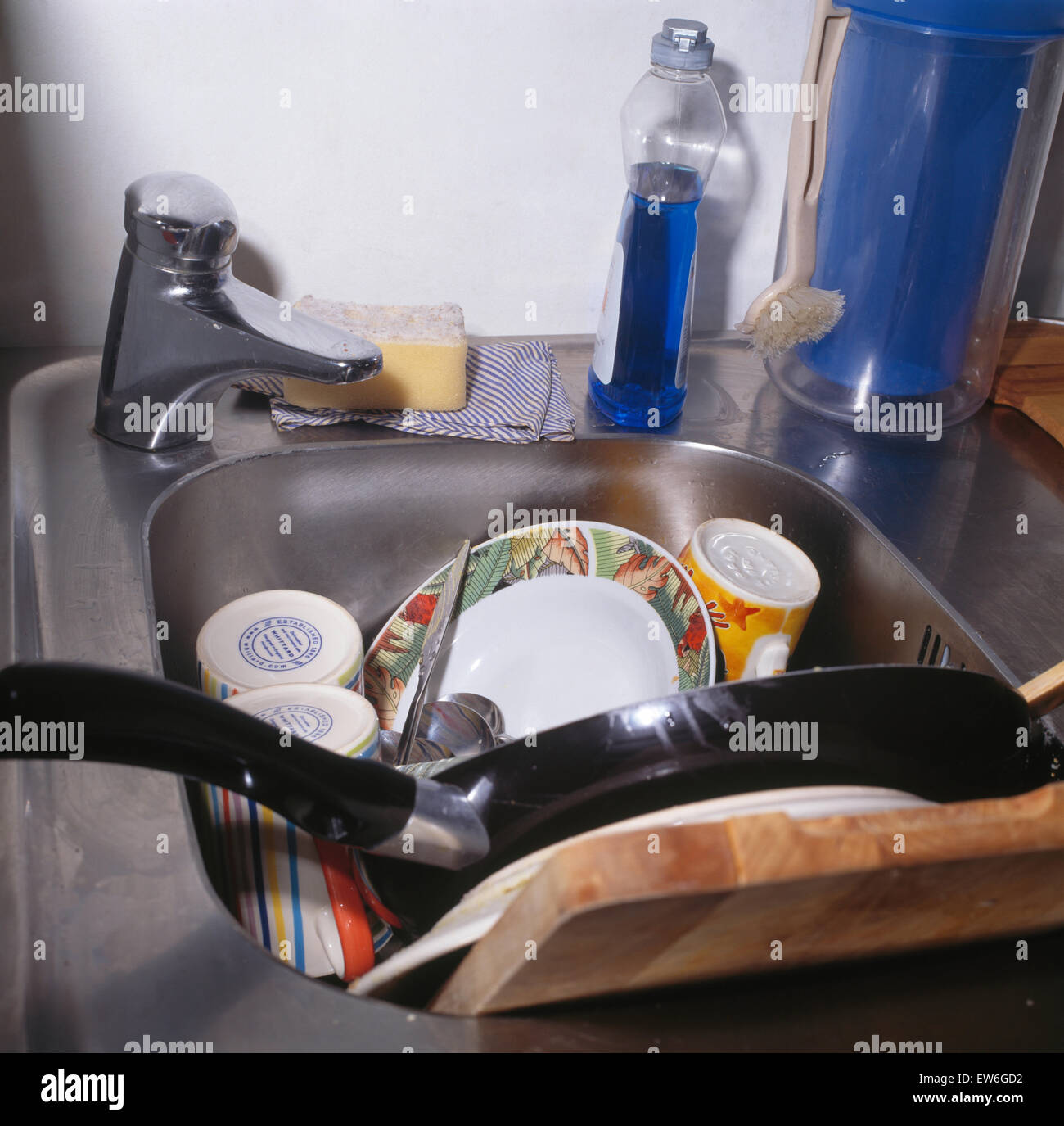 Sink piled with unwashed crockery in untidy kitchen Stock Photo