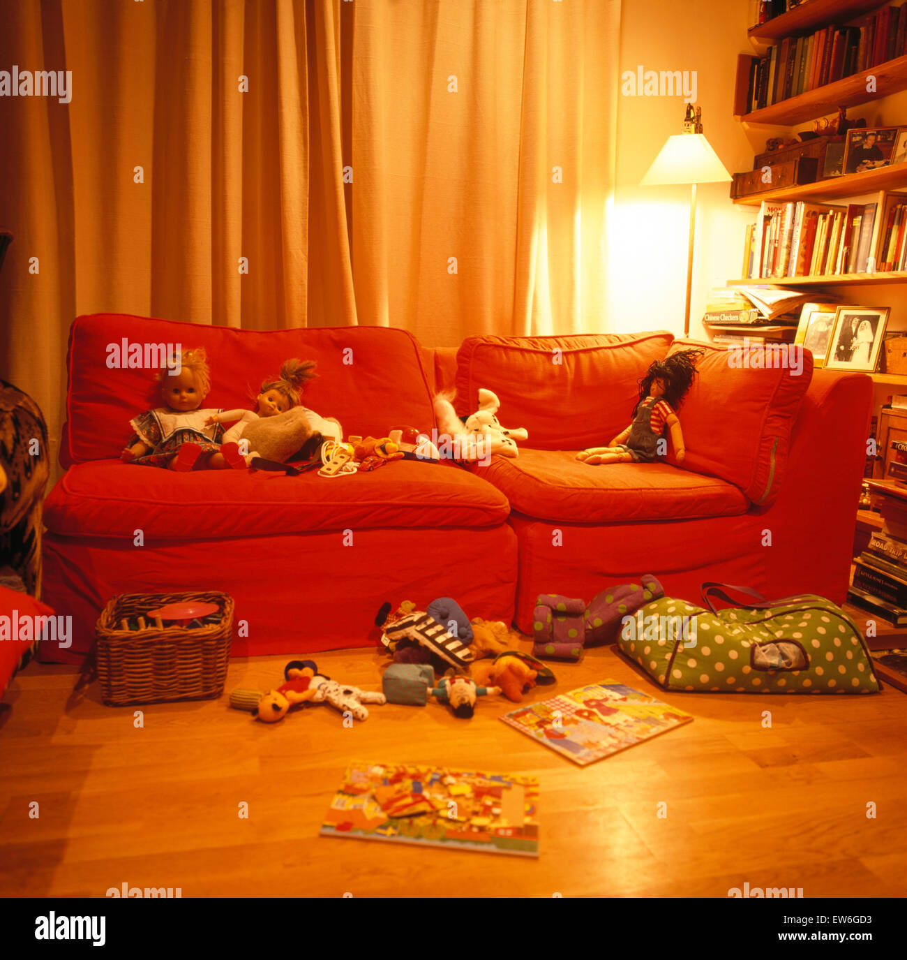 Toys on orange sofa and floor in children's untidy play room Stock Photo