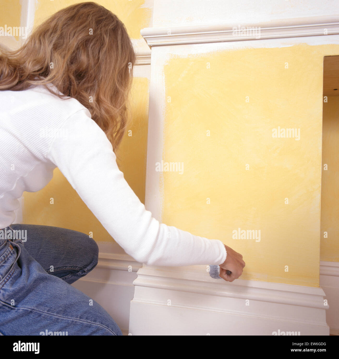 Woman painting a room with white paint Stock Photo