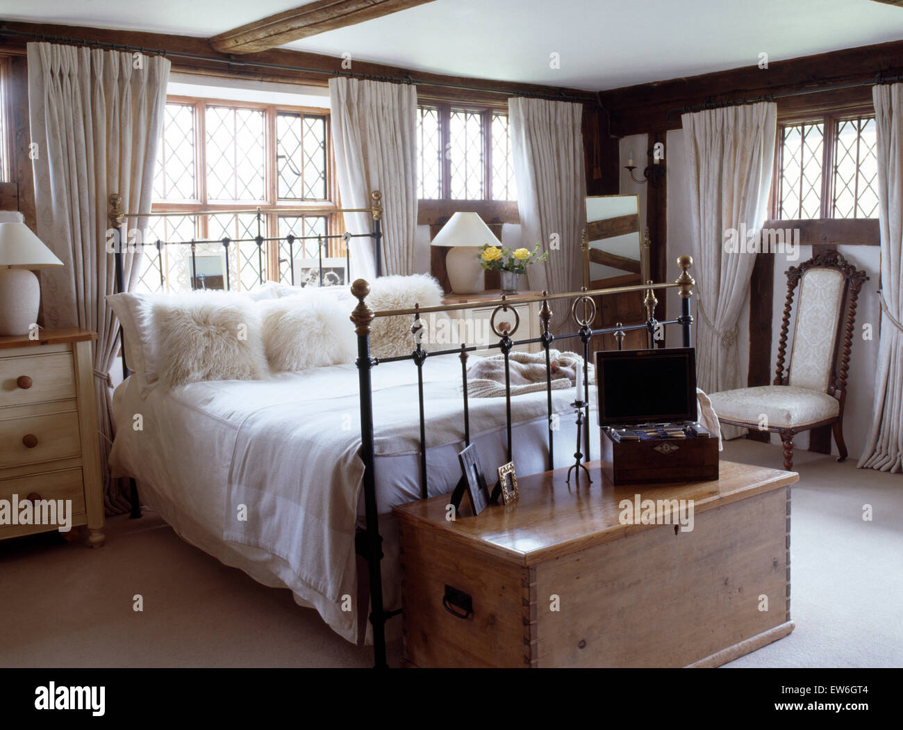 Fluffy white cushions and white linen on antique brass bed in country