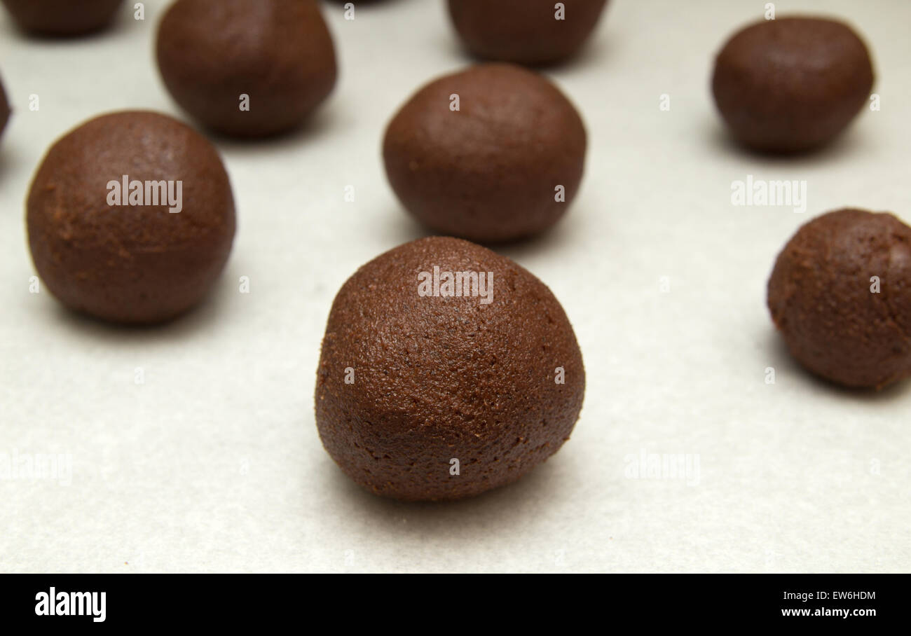 making chocolate cookies - small balls of chocolate mix on baking parchment Stock Photo