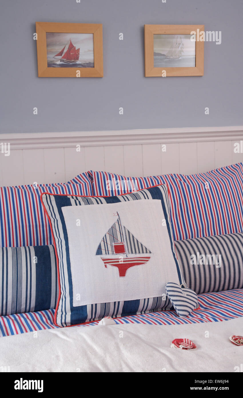 Striped and appliqued cushions with nautical theme on bed in coastal cottage bedroom Stock Photo