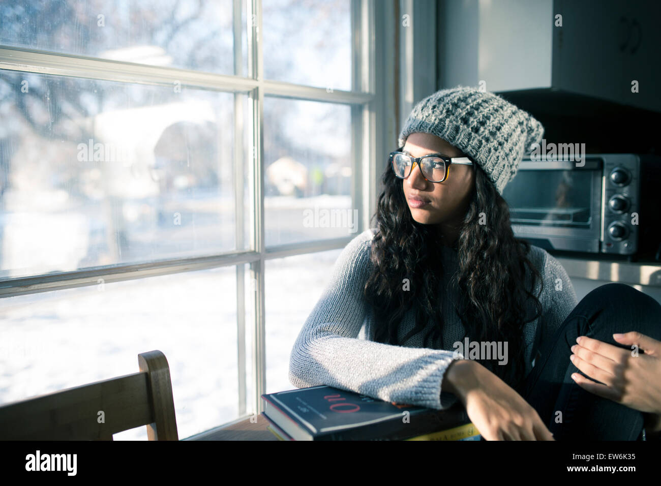 A young African-America college girl stares out a window instead of studying. Stock Photo
