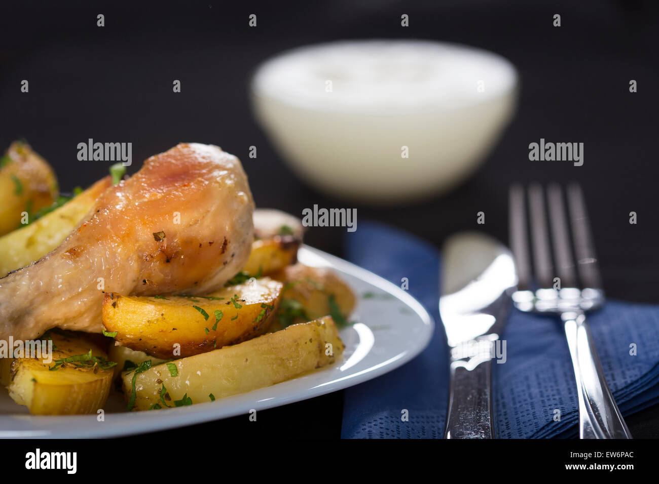 Baked potatoes with roasted chicken drumstick on white plate Stock Photo