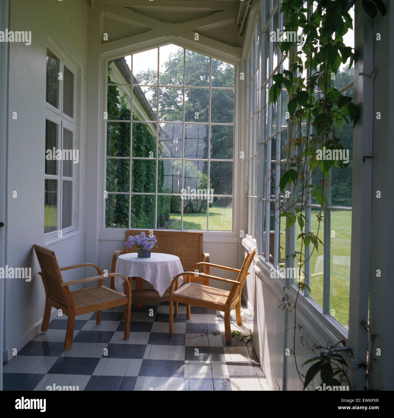 Simple chairs and wicker sofa at small table in Scandinavian