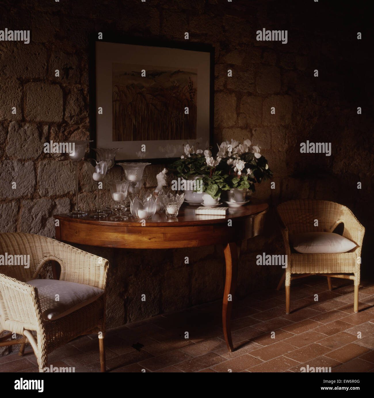 Wicker chairs either side of console table with collection of glass