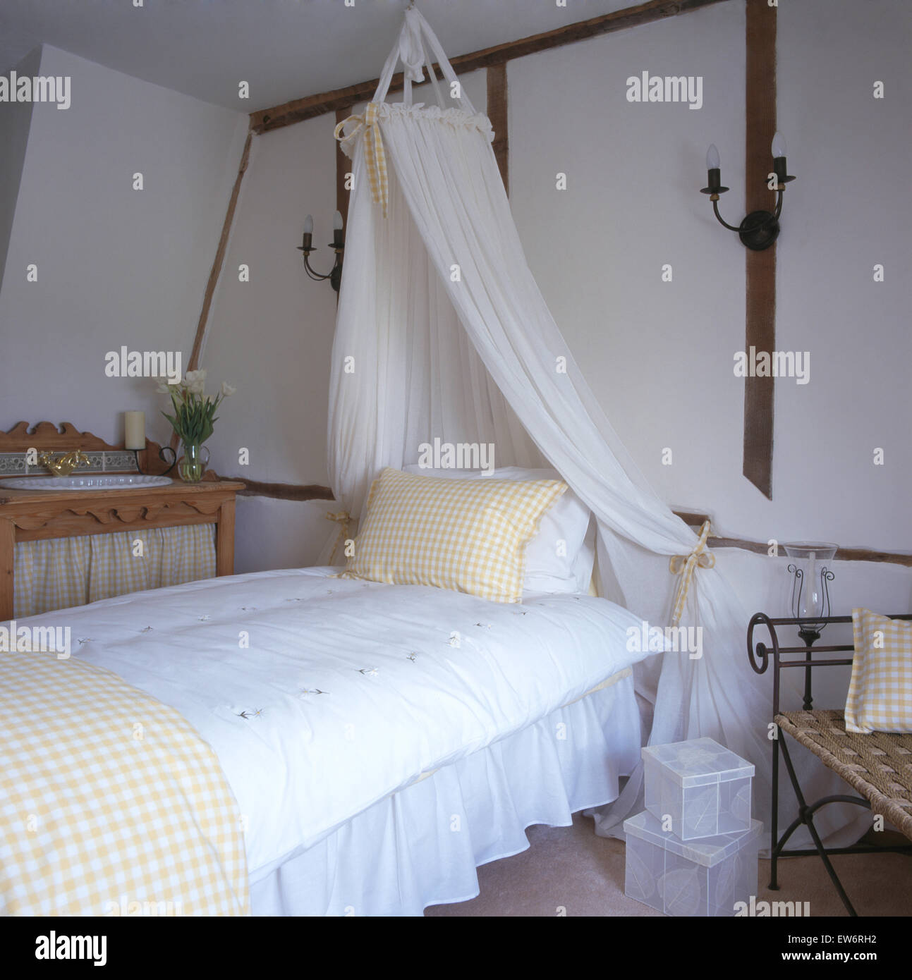 Coronet with white voile drapes above bed with white duvet in nineties cottage bedroom Stock Photo