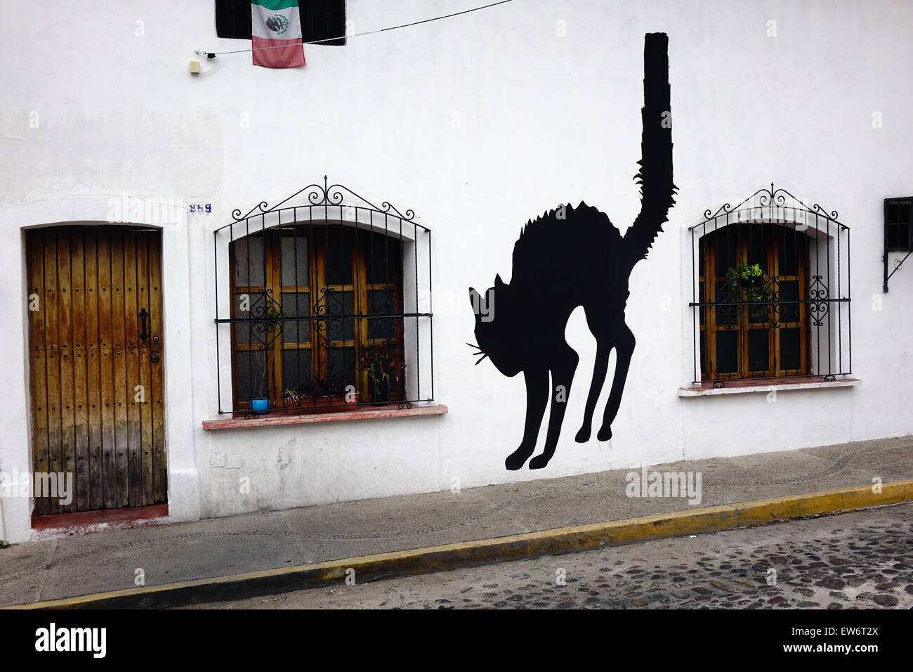 Black cat painted on wall, downtown Puerto Vallarta, Mexico. Mexican flag is at upper left Stock Photo