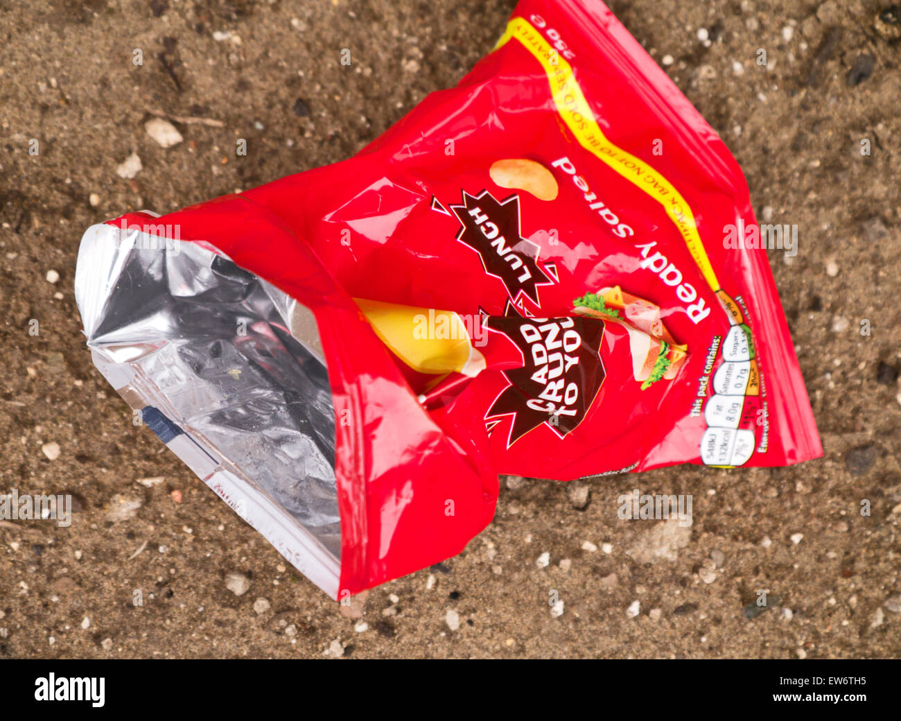 Discarded empty red potato crisps/chips, packet on soil background Stock Photo