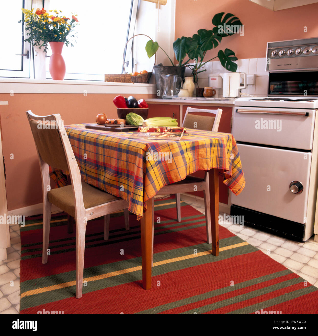 Wooden chairs at table with plaid cloth in economy style nineties kitchen Stock Photo