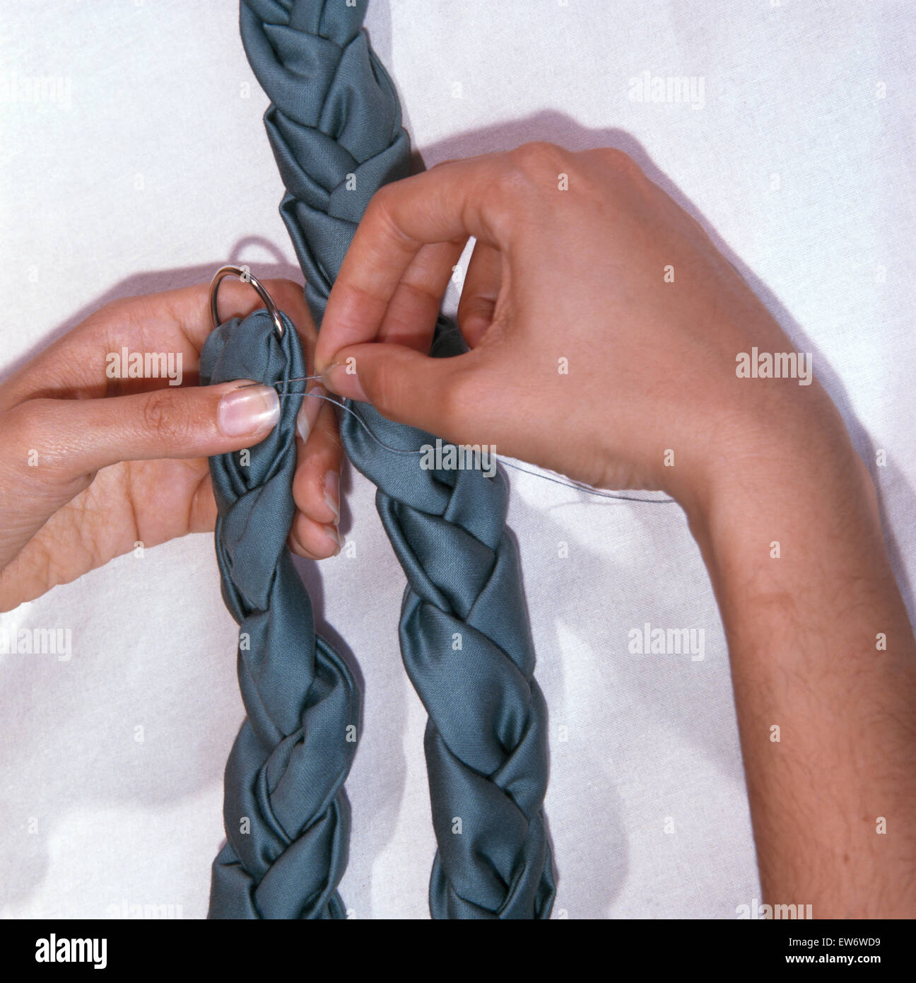 Closeup of hands sewing a blue plaited tie back Stock Photo Alamy