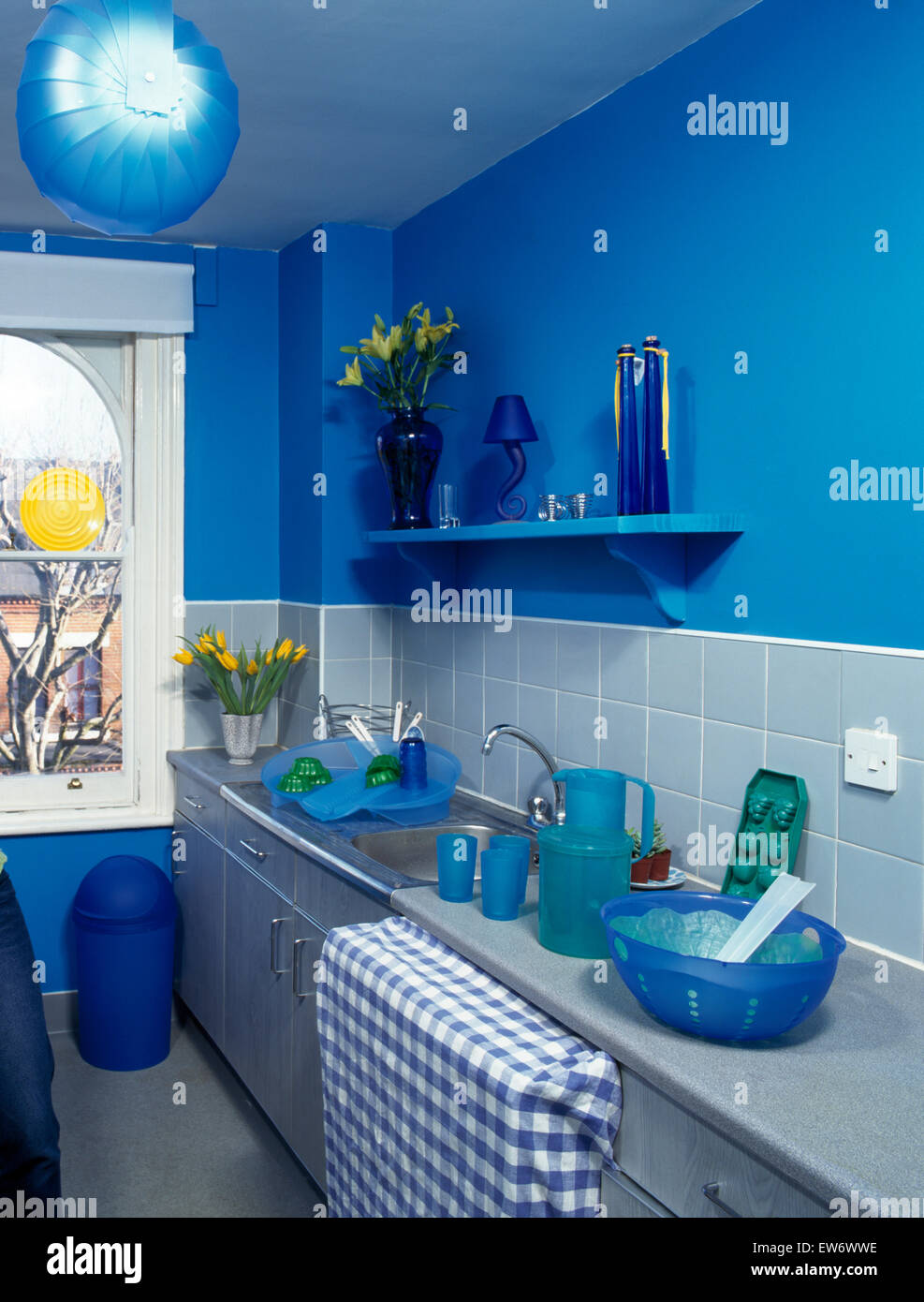 Bright blue nineties economy style kitchen with silver painted units Stock Photo