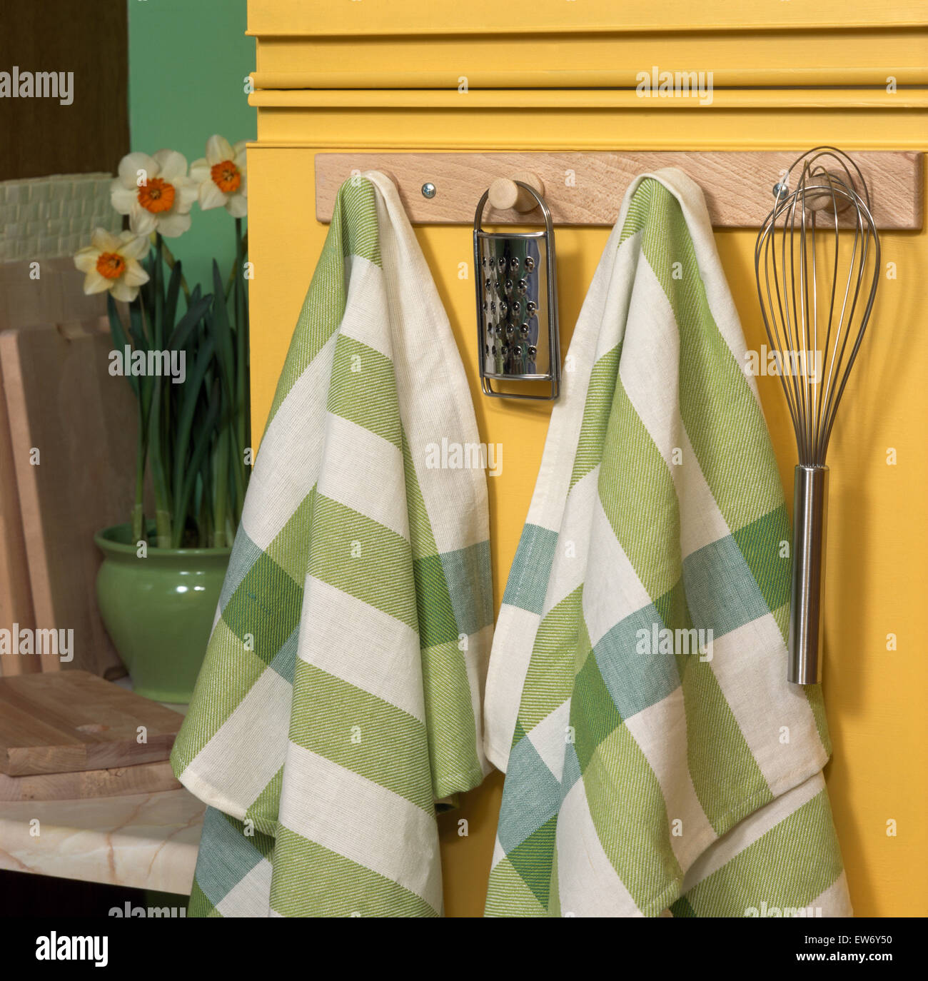 https://c8.alamy.com/comp/EW6Y50/close-up-of-green-checked-tea-towels-on-a-peg-board-with-kitchen-utensils-EW6Y50.jpg