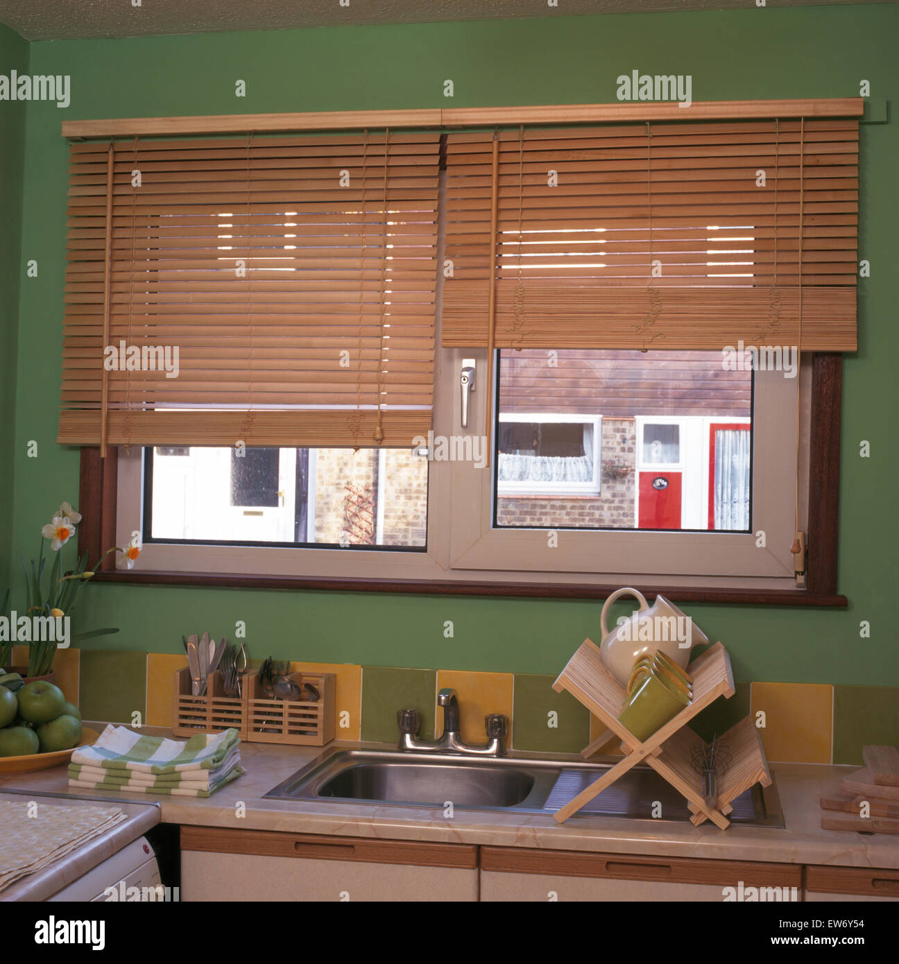 Wooden blind on window above sink in economy style kitchen Stock Photo Alamy
