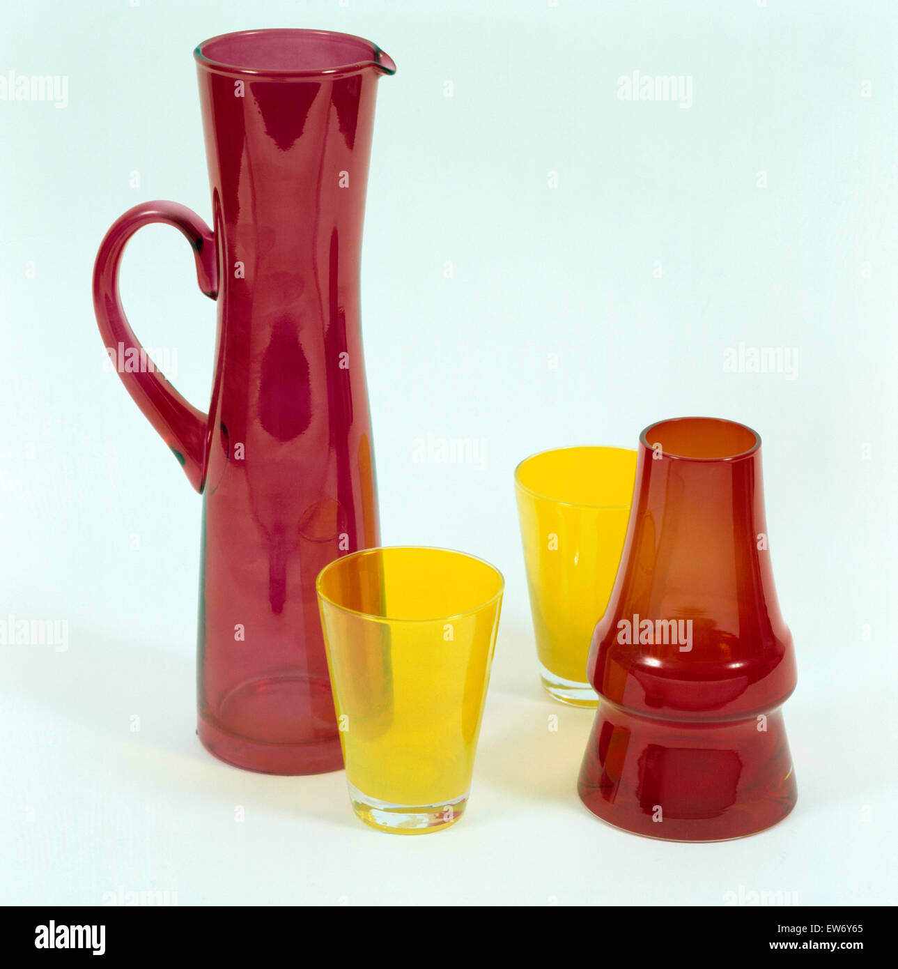 Closeup of a dark red glass jug and vase with two yellow glasses Stock