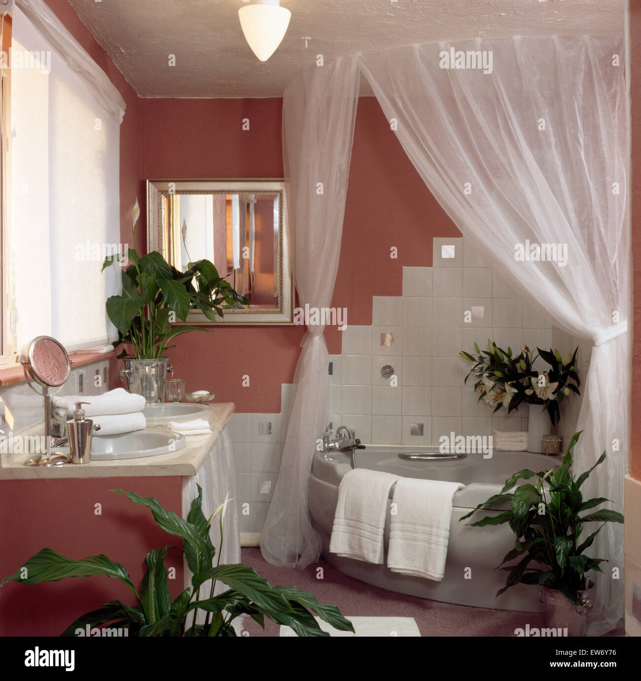 White drapes on corner bath with white tiled splash back in pink