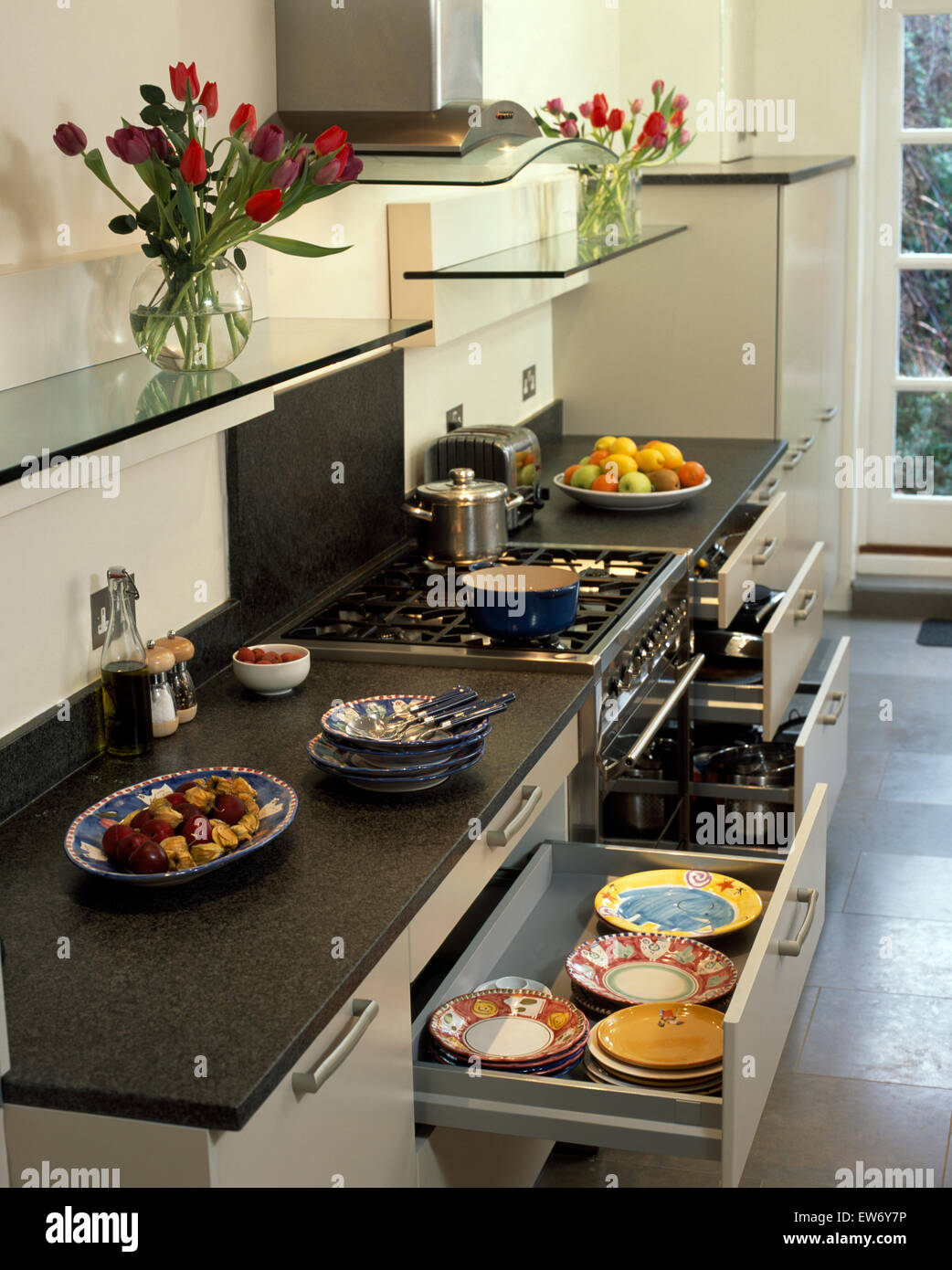 https://c8.alamy.com/comp/EW6Y7P/glass-shelves-above-fitted-units-with-slate-worktops-and-drawers-open-EW6Y7P.jpg
