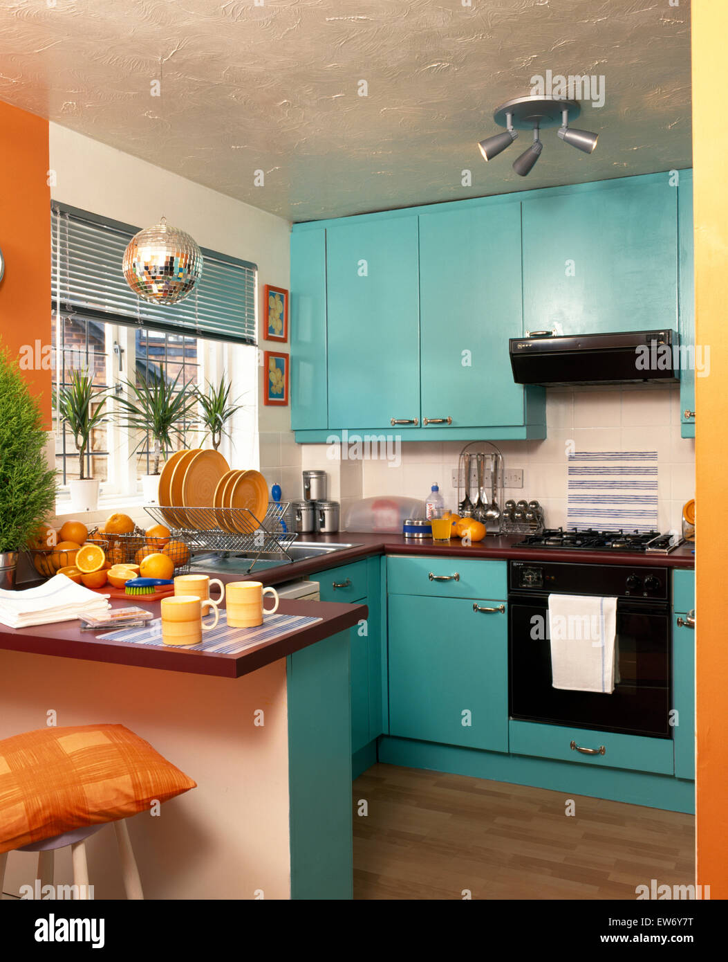 Turquoise doors on fitted units in nineties economy style kitchen Stock Photo