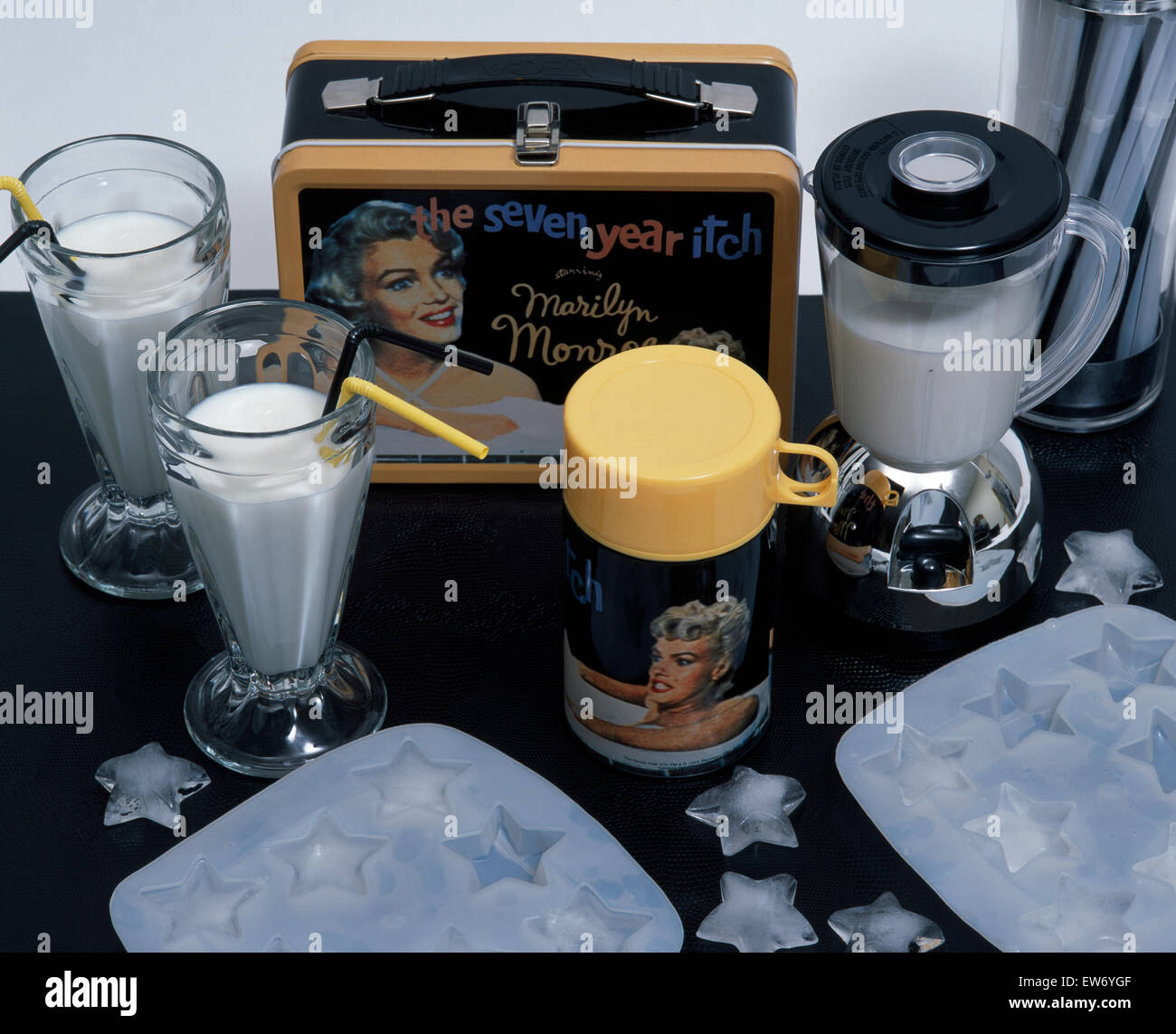 Glasses of milk shake with a Hollywood themed plastic beaker and miniature case beside an electric blender Stock Photo