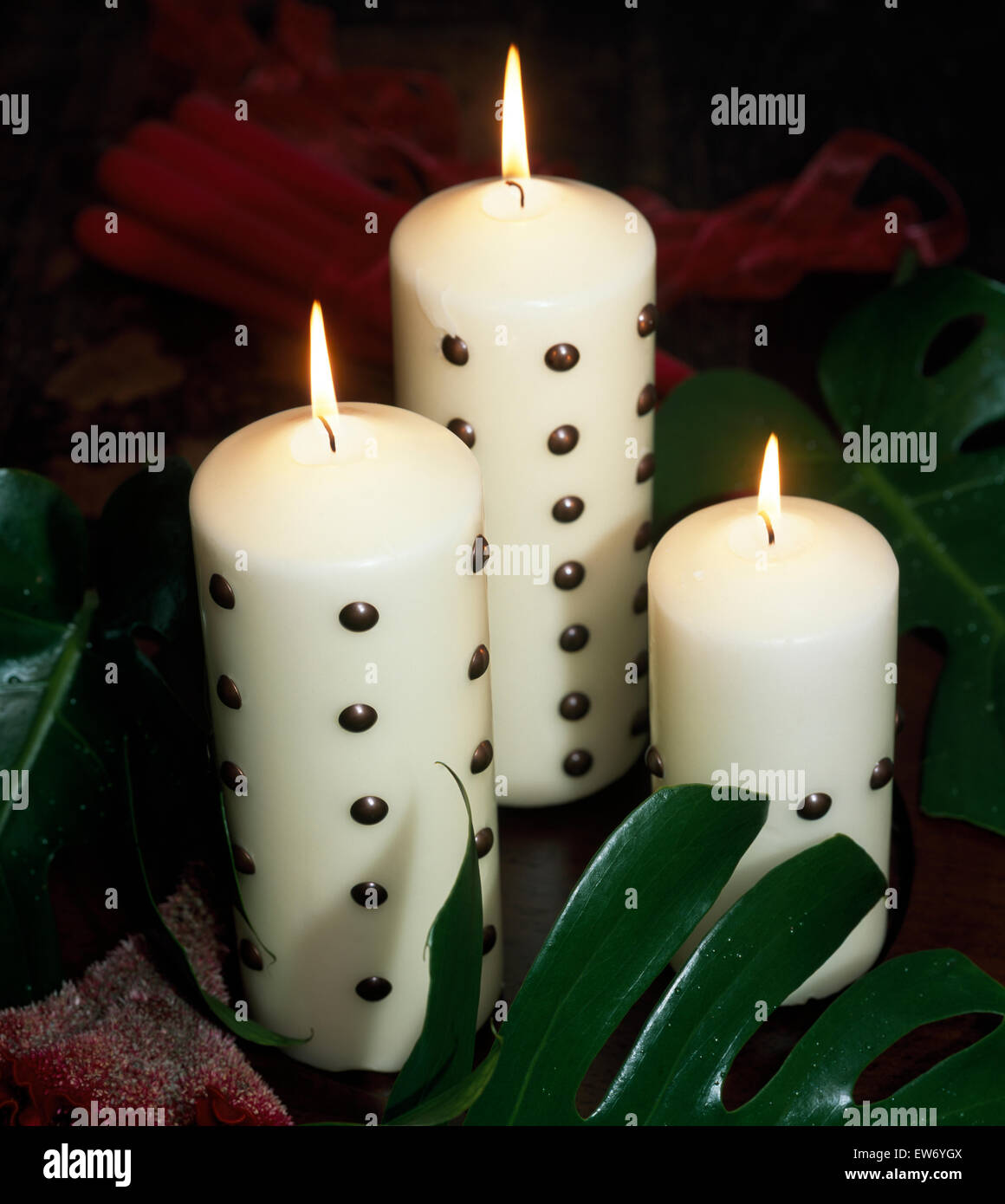 Close Up Of Three White Pillar Candles Decorated With Metal Studs