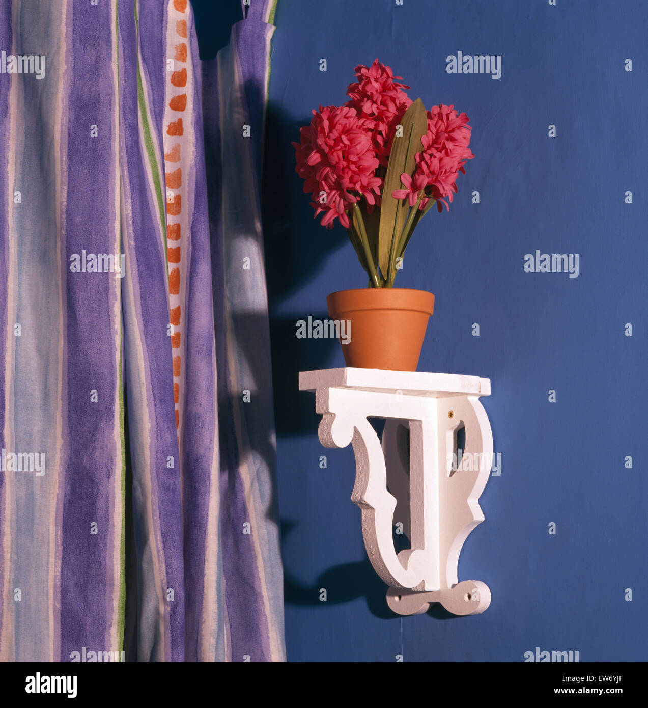 Close-up of a pot of artificial hyacinths on a small white wooden shelf Stock Photo