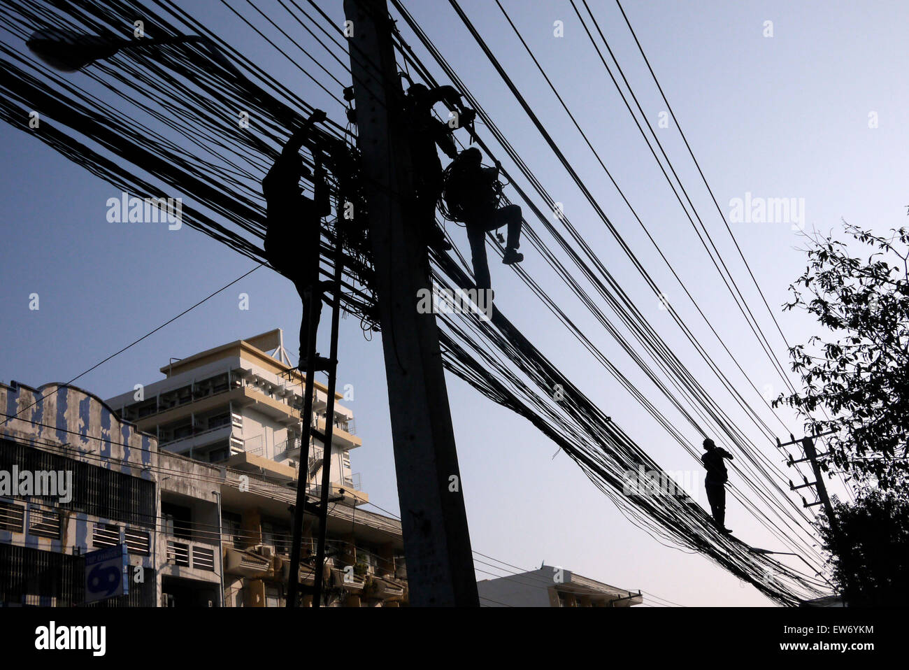 Electrical cable fitters working in a dangerous situation above a city street in Pattaya Thailand Stock Photo