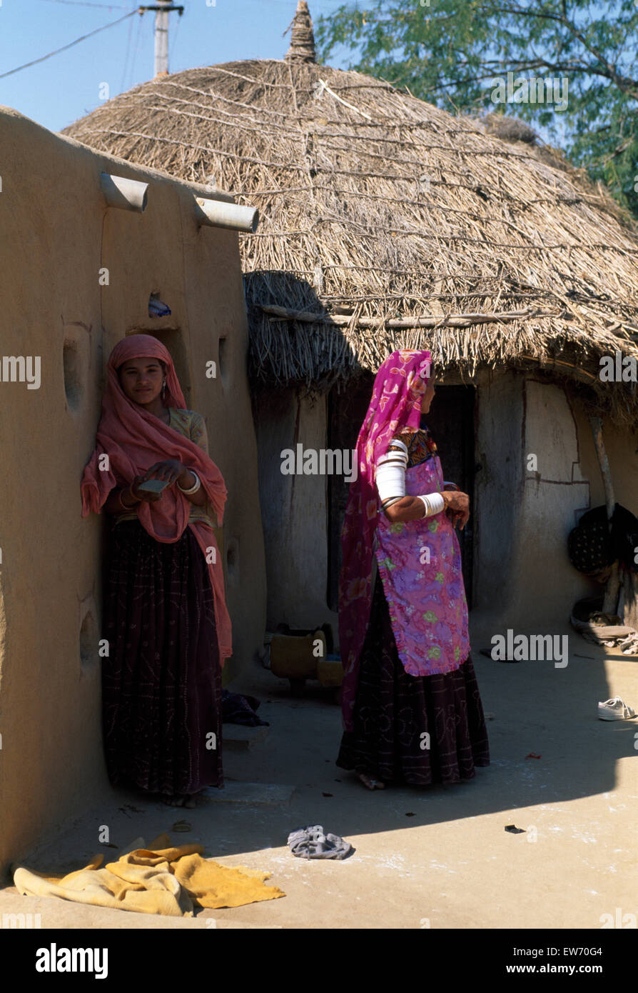 Two young Indian women wearing colorful saris standing in the shade of a hut in an Indian village         FOR EDITORIAL USE ONLY Stock Photo